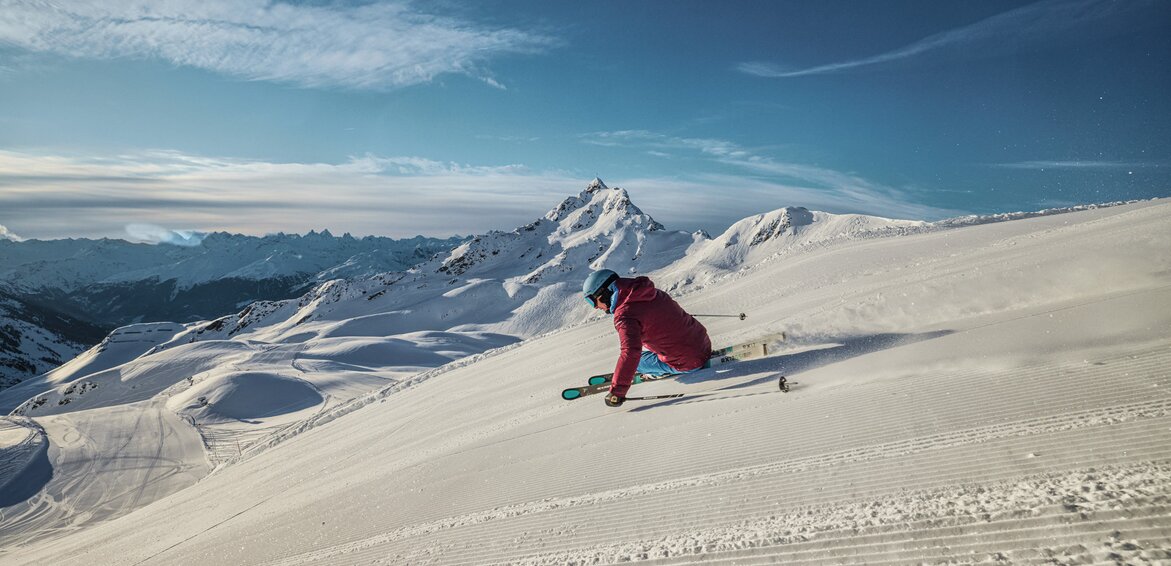 Ein Skifahrer fährt am Morgen über die frisch präparierte Piste mit der Zamangspitze im Hintergrund. | © Silvretta Montafon - Stefan Kothner