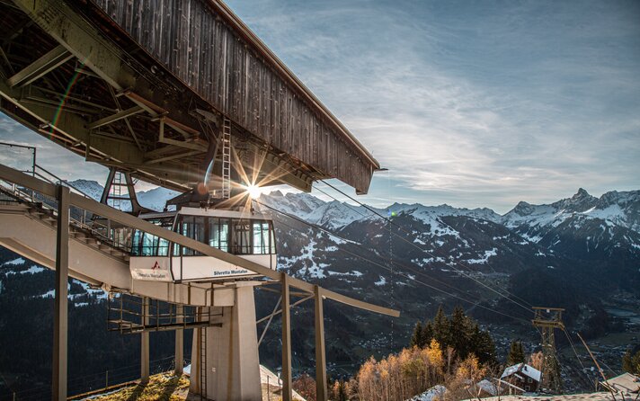 Hochjoch Bahn im Herbst - Silvretta Montafon | © Silvretta Montafon - Frederike Weber Eine Kabinenbahn fährt in die Bergstation bei Abendsonne und verschneiten Bergspitzen. | © Silvretta Montafon - Frederike Weber