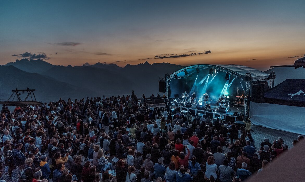 Ein Konzert beim Sonnenuntergang mit bunter Beleuchtung und großem Publikum | © Silvretta Montafon