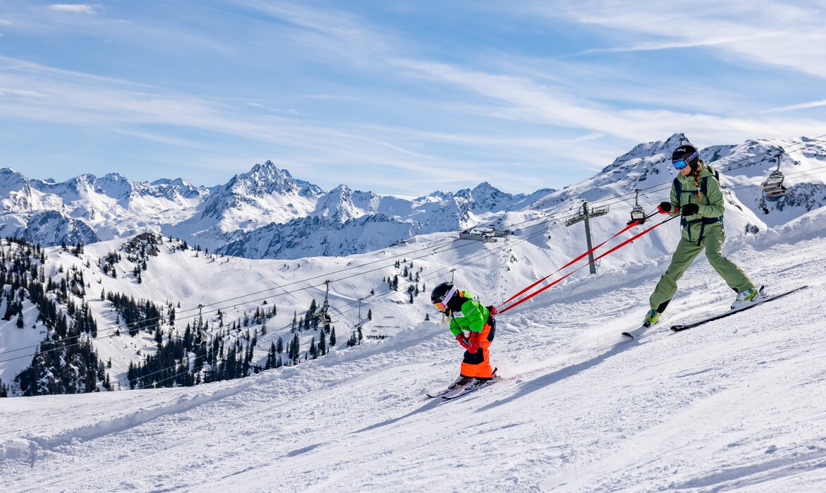 Eine Mutter übt mit Ihrem Kind am Gurt den Pflug beim Skifahren in der Silvretta Montafon. | © Silvretta Montafon - Torsten Wenzler