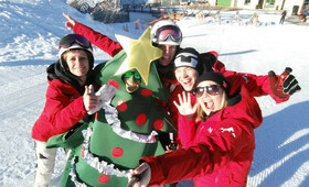 Das Team der Silvretta Montafon macht ein Selfie auf der Piste mit einem Mann verkleidet als Weihnachtsbaum