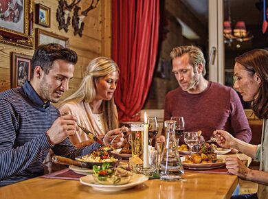Vier Personen sitzen an einem Tisch und genießen Gerichte beim Haxenabend