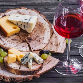 Ein Weinglas mit Käse und Brot auf einer Holzscheibe