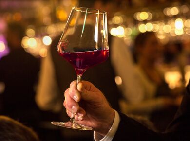 Eine Person hält ein großes Weinglas gefüllt mit Rotwein in der Hand