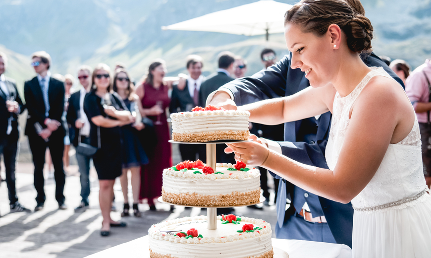 Braut beim Kuchenanschnitt mit unglaublichen Bergpanorama im Hintergrund