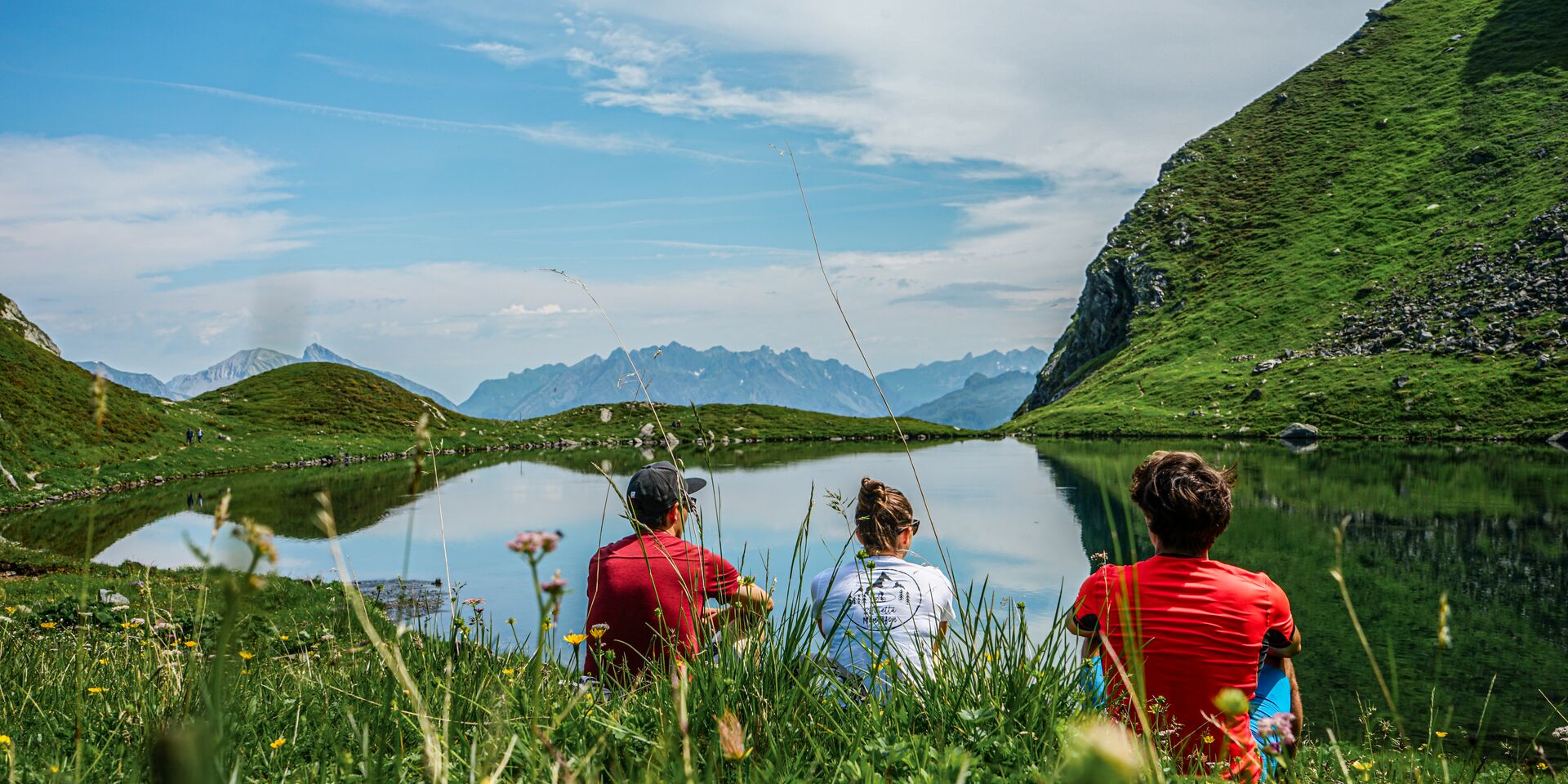 3 Personen schauen zu einem Bergsee hinaus am HochJoch