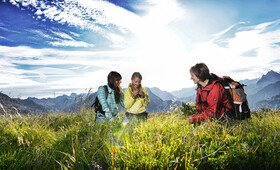 Eine Gruppe sammelt frische Kräuter bei der Kräuterwanderung in den Bergen Montafons