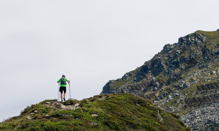 Ein Teilnehmer des Montafon Totale Trails wandert den steilen Berg hinauf mit der Bergspitze in Sicht
