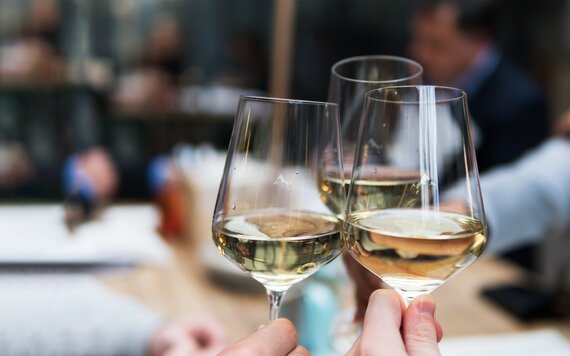 Drei Weingläser mit Silvretta Montafon Logo gefüllt mit Weißwein stossen an