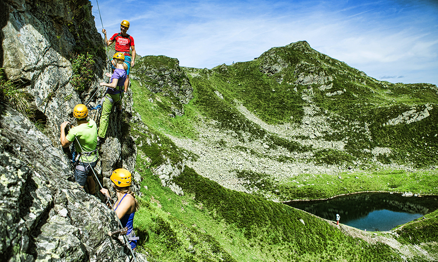 Eine Gruppe mit Kletterausrüstung klettert den Klettersteig Kälbersee entlang im Sommer