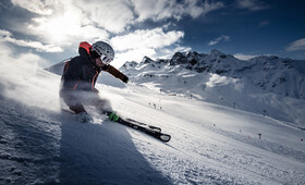 Ein Skifahrer zieht eine Kurve auf der frischen Piste im Sonnenschein