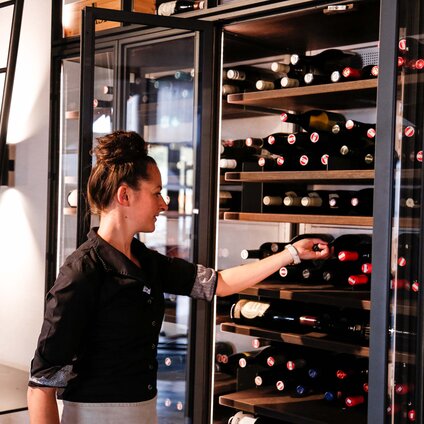 Eine Servicekraft holt den Wein aus dem Wein-Akklimatisierer  | © Silvretta Montafon -  Friederike Weber