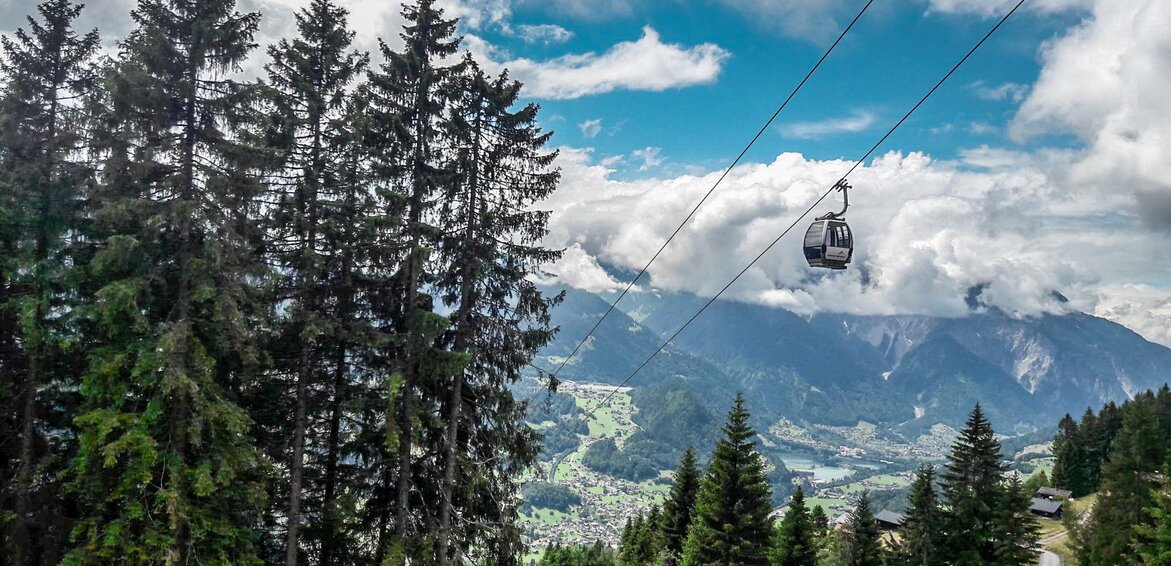 Die Zamang Bahn schwebt über dem Wald mit Wolken im Hintergrund zur Bergstation hoch. | © Silvretta Montafon