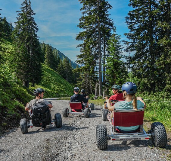 Eine Gruppe steht mit den Gravity Carts auf einer Bergstrasse in der Silvretta Montafon. | © Silvretta Montafon - Vanessa Strauch