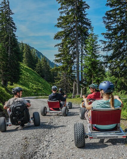 Eine Gruppe steht mit den Gravity Carts auf einer Bergstrasse in der Silvretta Montafon. | © Silvretta Montafon - Vanessa Strauch