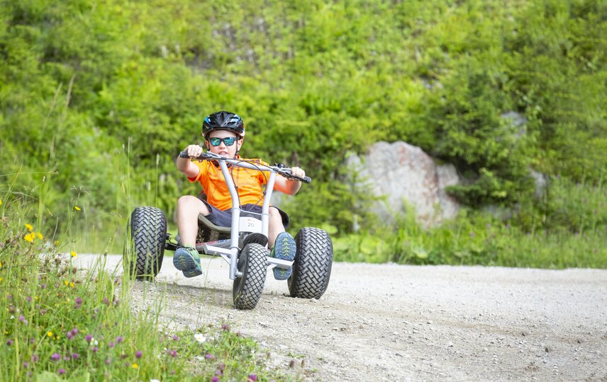 Eine Junge fährt auf einem Mountaincart einen Weg entlang. | © Silvretta Montafon