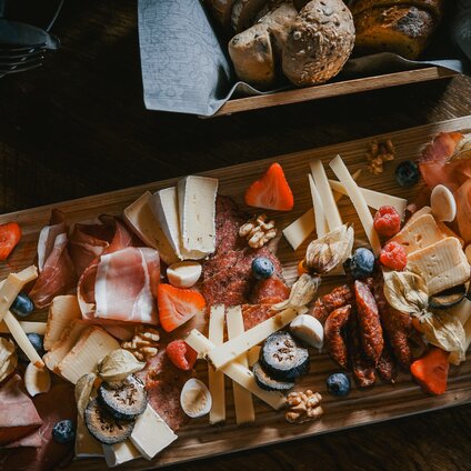 Ein Tisch mit Käsebrett, Brotkörbchen und Wein. | © Silvretta Montafon - Vanessa Strauch