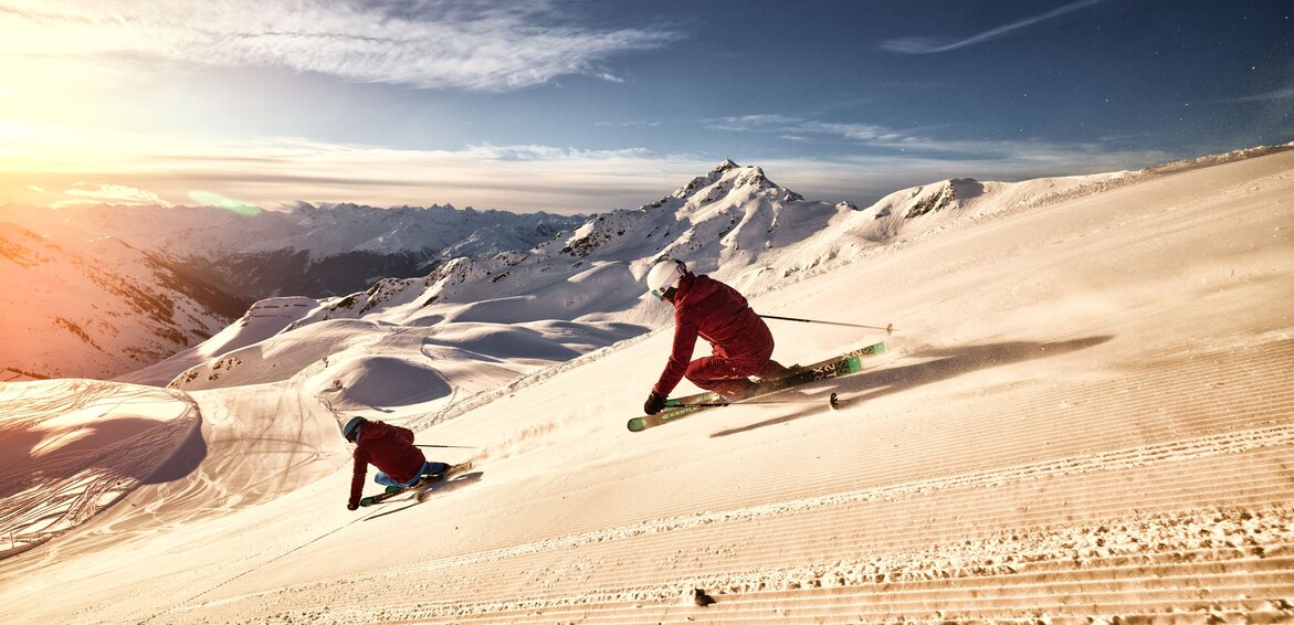 Zwei sportliche Skifahrer bei aufgehender Sonne auf der Skipiste in der Silvretta Montafon. | © Silvretta Montafon - Stefan Kothner