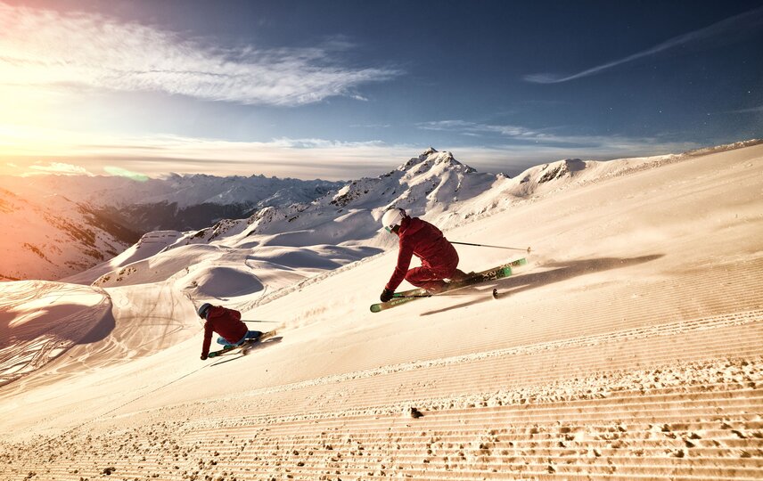 Zwei sportliche Skifahrer bei aufgehender Sonne auf der Skipiste in der Silvretta Montafon. | © Silvretta Montafon - Stefan Kothner