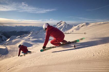 Zwei sportliche Skifahrer bei aufgehender Sonne auf der Skipiste in der Silvretta Montafon. | © Silvretta Montafon - Stefan Kothner