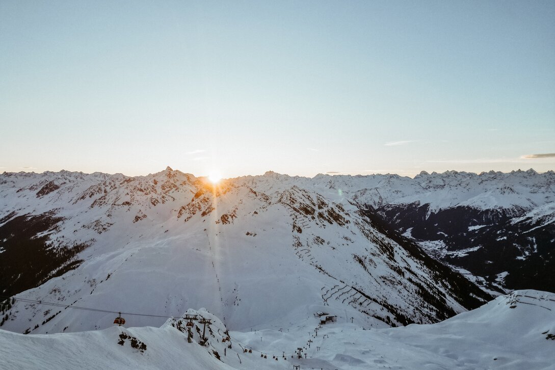 Die Sonne geht hinter den verschneiten Bergen der Silvretta Montafon auf. | © Silvretta Montafon - Vanessa Strauch