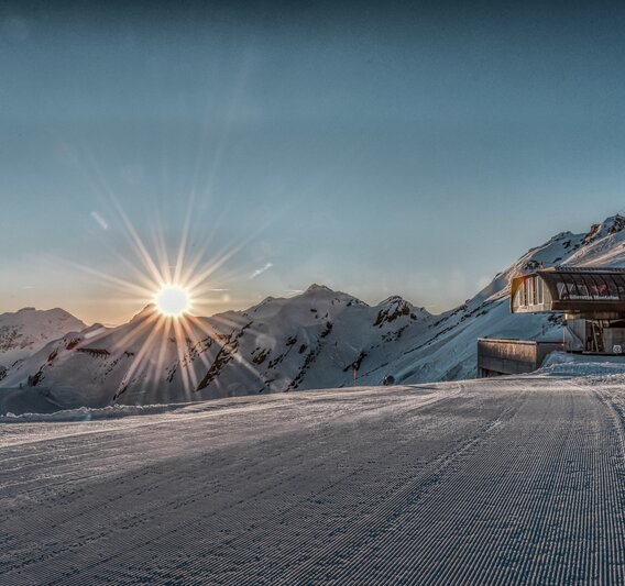 Ein Sonnenaufgang an einer Bergstation im Skigbiet mit frisch präparierten Pisten im Vordergrund. | © Silvretta Montafon - Jutta Detjen