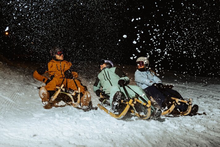 Drei Freunde rodeln in der Nacht bei der Nachtrodelnbahn Garfrescha | © Silvretta Montafon - Marie Schilcher