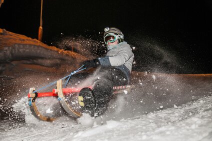 Eine Person beim Nachtrodeln im Schnee. | © Silvretta Montafon - Marcel Mehrling