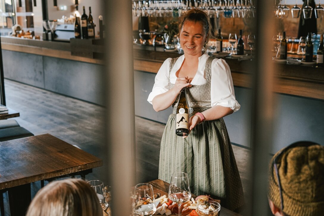 Eine Kellernin im Dirndl erklärt den Wein vor der Verköstigung. | © Silvretta Montafon - Vanessa Strauch
