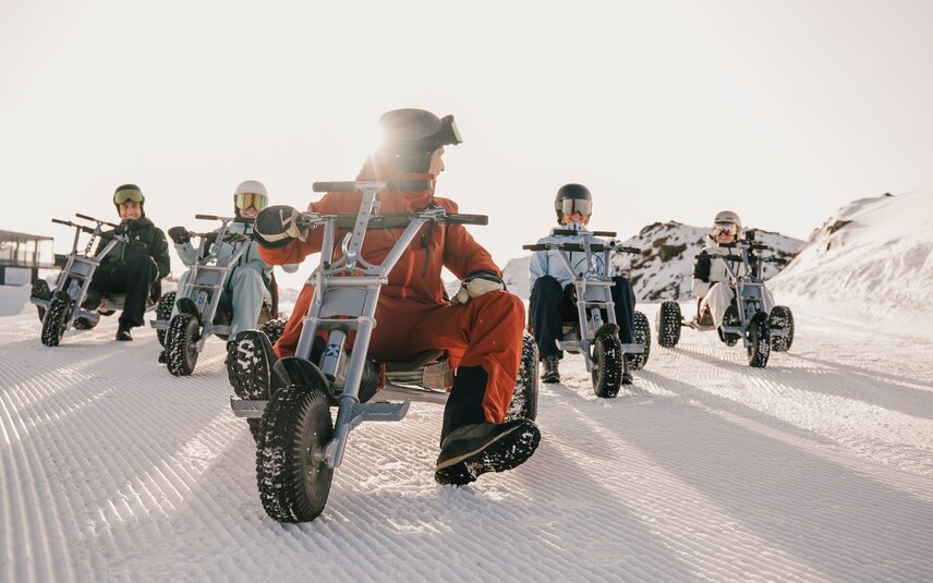 Fünf Personen auf einem Mountaincart auf einer Skipiste am Morgen bei Sonnenaufgang. | © Silvretta Montafon - Niklas Kirchler