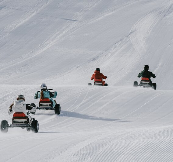 Vier Personen fahren auf einem Mountaincart auf einer Skipiste. | © Silvretta Montafon - Niklas Kirchler
