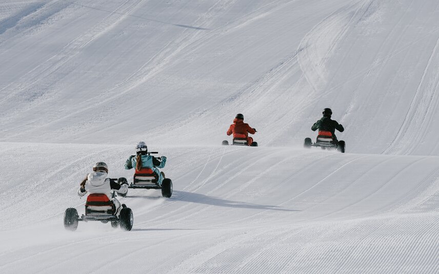 Vier Personen fahren auf einem Mountaincart auf einer Skipiste. | © Silvretta Montafon - Niklas Kirchler