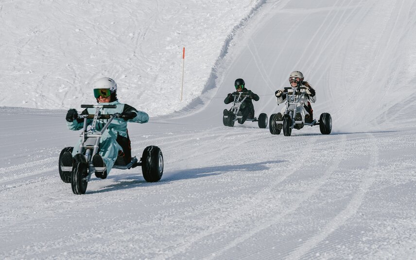 Drei Personen fahren auf einem Mountaincart auf einer Skipiste. | © Silvretta Montafon - Niklas Kirchler