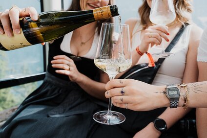 Eine junge Frau schenkt Wein in ein Weinglas in einer Gondel ein | © Silvretta Montafon - GOODGUYPAEZ