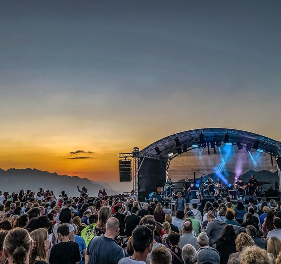 Ein Konzert beim Sonnenuntergang mit bunter Beleuchtung und großem Publikum | © Silvretta Montafon