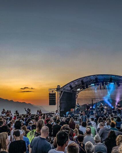 Ein Konzert beim Sonnenuntergang mit bunter Beleuchtung und großem Publikum | © Silvretta Montafon