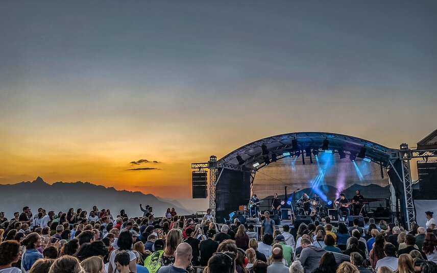 Ein Konzert beim Sonnenuntergang mit bunter Beleuchtung und großem Publikum | © Silvretta Montafon