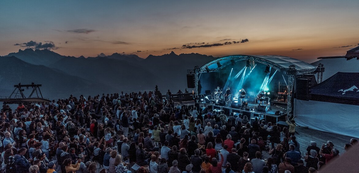 Ein Konzert beim Sonnenuntergang mit bunter Beleuchtung und großem Publikum | © Silvretta Montafon