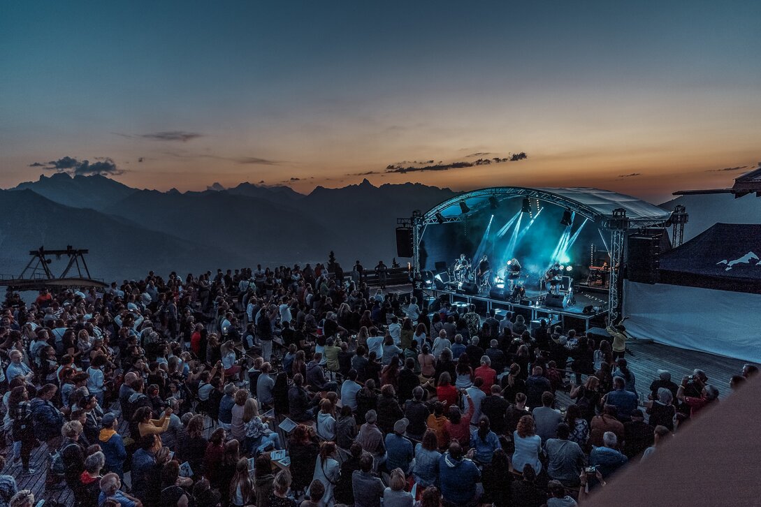 Ein Konzert beim Sonnenuntergang mit bunter Beleuchtung und großem Publikum | © Silvretta Montafon