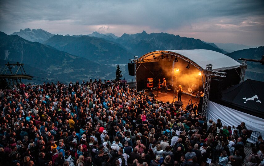 Ein Konzert beim Sonnenuntergang mit bunter Beleuchtung und großem Publikum | © Silvretta Montafon - Frederike Weber