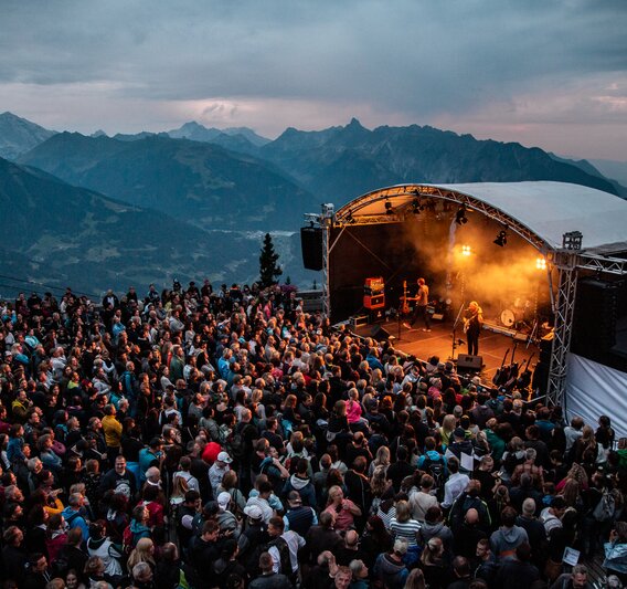 Ein Konzert beim Sonnenuntergang mit bunter Beleuchtung und großem Publikum | © Silvretta Montafon - Frederike Weber