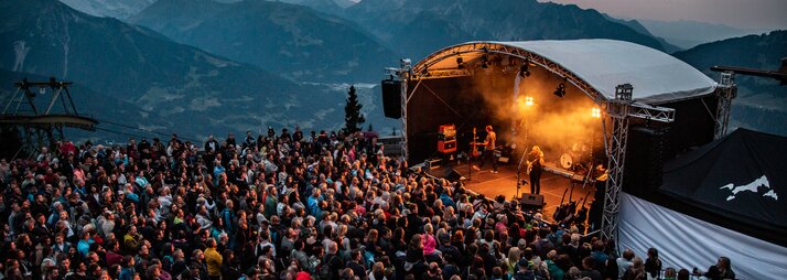 Ein Konzert beim Sonnenuntergang mit bunter Beleuchtung und großem Publikum | © Silvretta Montafon - Frederike Weber