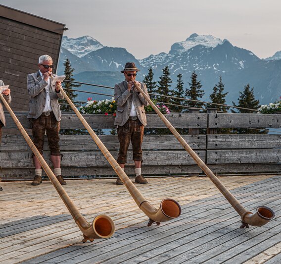 Drei Alphorngläser spielen auf einer Terrasse in den Bergen der Silvretta MOntafon. | © Silvretta Montafon - Vanessa Strauch
