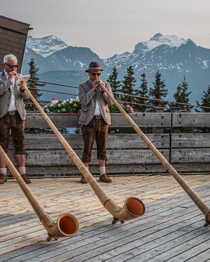 Drei Alphorngläser spielen auf einer Terrasse in den Bergen der Silvretta MOntafon. | © Silvretta Montafon - Vanessa Strauch