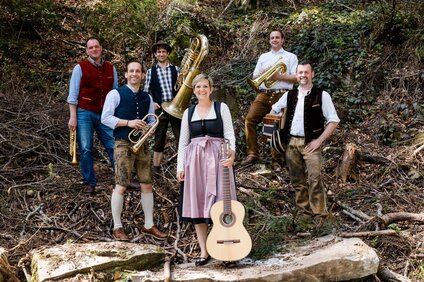 Fünf Musikanten in Dirndl und Lederhose mit ihren Instrumenten | © Alpdudler