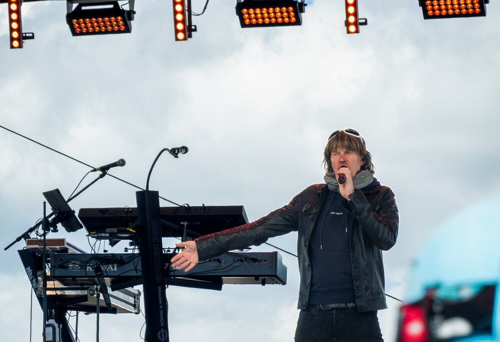 Mickie Krause in schwarzer Bekleidung singt auf der Bühne in den Bergen | © Silvretta Montafon - VONIHR Productions