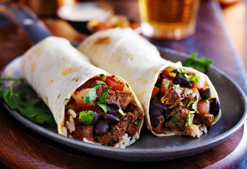 Zwei mit Fleisch und Gemüse gefüllte Burritos auf einem Teller | © Silvretta Montafon - Fotolia