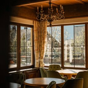 Gemütlicher Sitzbereich vor einem Fenster mit Aussicht auf die Berge im Hotel Cresta in Tschagguns | © Silvretta Montafon – Vanessa Strauch