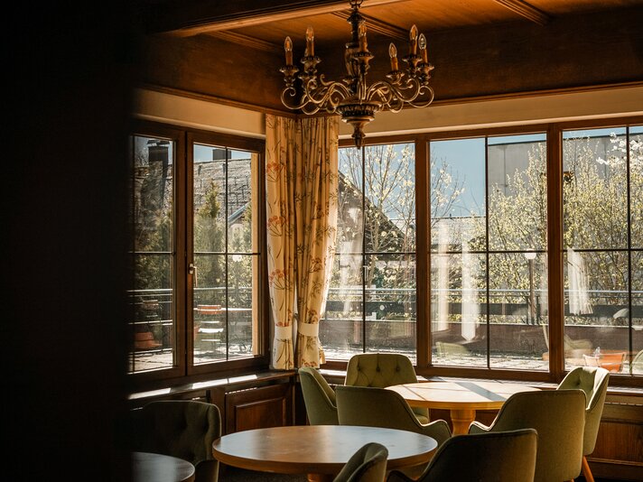 Gemütlicher Sitzbereich vor einem Fenster mit Aussicht auf die Berge im Hotel Cresta in Tschagguns | © Silvretta Montafon – Vanessa Strauch