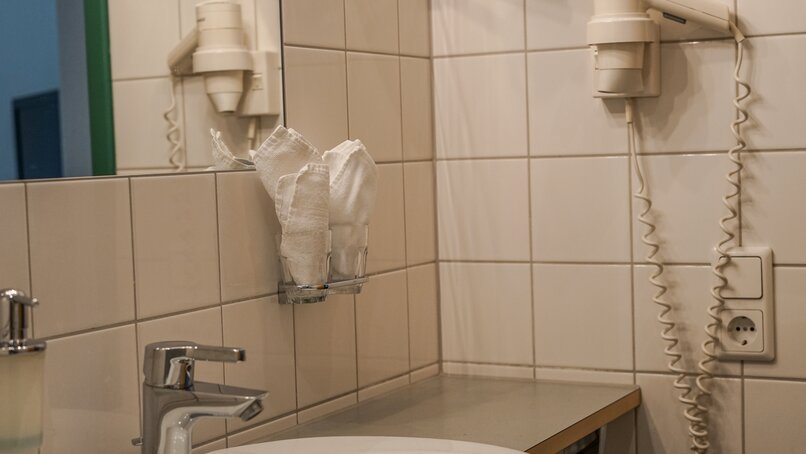Badezimmer mit einem weißen Waschbecken und weißen Fließen im Hotel Cresta in  Tschagguns | © Silvretta Montafon – Vanessa Strauch